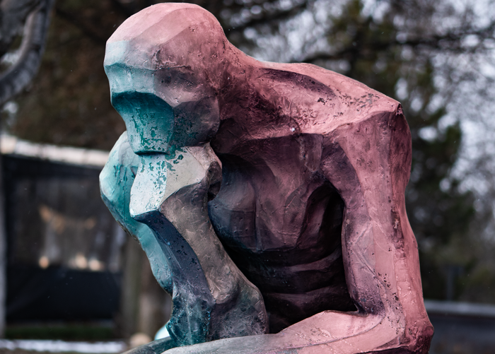 Home A vibrant abstract sculpture of a thinker situated in an outdoor park setting.